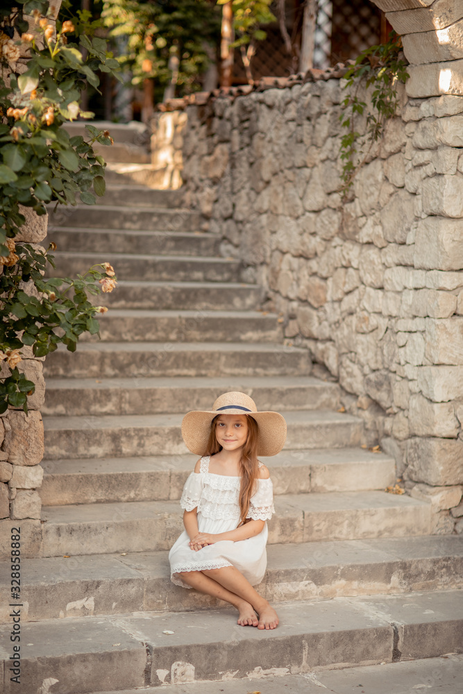 A girl in a lace straw hat sits on stone steps. A girl in a lace straw hat sits on stone steps.