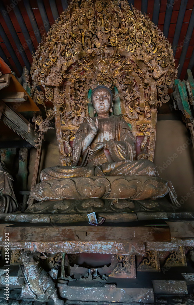 Ancient statue of buddha in ancient altar with carved details in wood. Altar figure located in Shuanglin Temple (or Zhongdu Temple), outskirts Pingyao Old City, Shanxi province, China