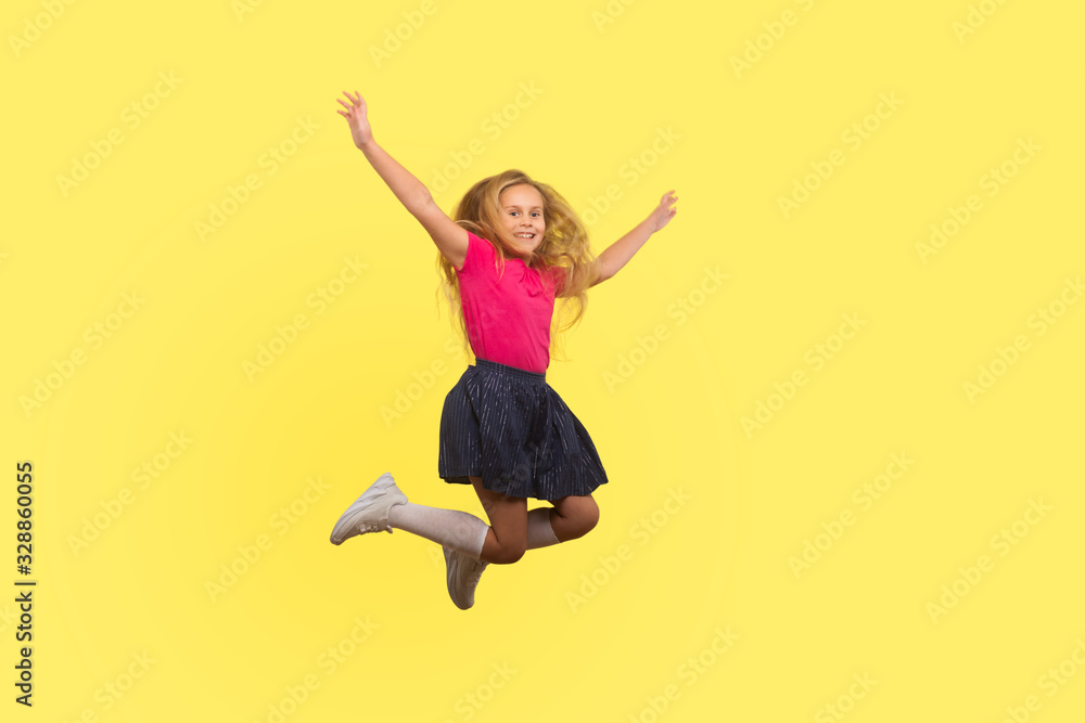 Full length portrait of beautiful little girl with long blond hair in dress jumping in air, inspired child flying and celebrating carefree life. indoor studio shot isolated on yellow background Full length portrait of beautiful little girl with long blond hair in dress jumping in air, inspired child flying and celebrating carefree life. indoor studio shot isolated on yellow background