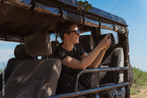 Young woman taking pictures from a safari vehicle in a natural park in sri lanka