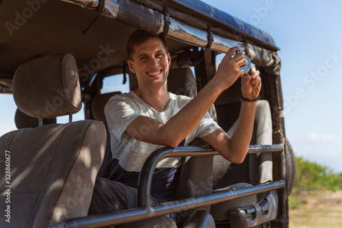 Young man taking pictures from a safari vehicle in a natural park in sri lanka