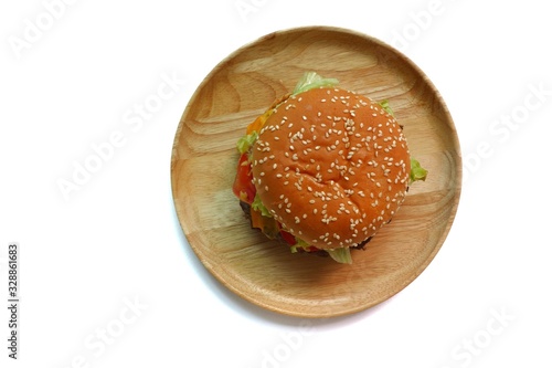 Overhead view of a single hamburger on a plain wooden plate, isolated clean white background studio lighting.