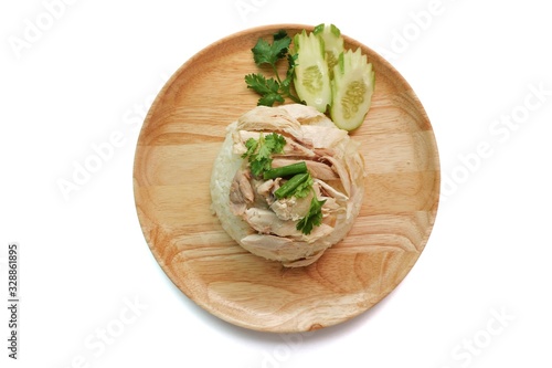 Top eye view closeups of Hainanese chicken rice or rice steamed with chicken soup Thai gourmet and slide cucumber in the soft wooden plate isolated on a white table background at a kitchen room