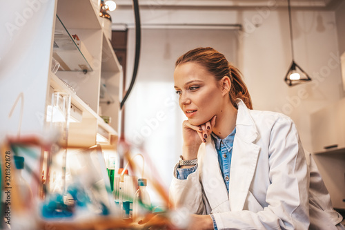 Woman working in laboratory. Working in lab. Portrait of confident female scientist working on laptop in chemical laboratory. Smiling female chemist using laptop for medical research in a laboratory