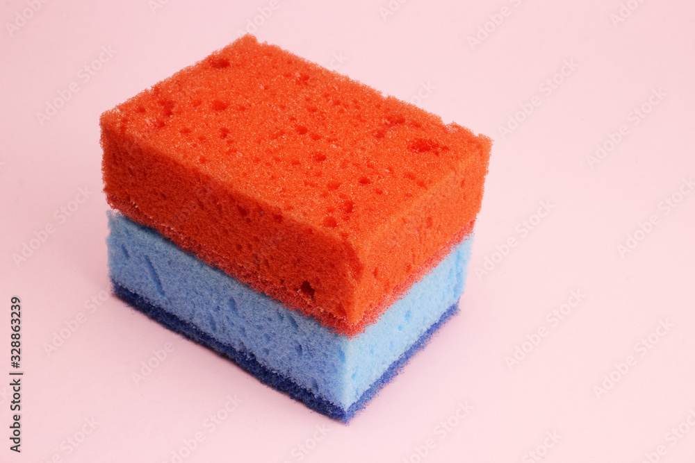 Blue and red sponge for dishes or cleaning on a pink background Blue and red sponge for dishes or cleaning on a pink background