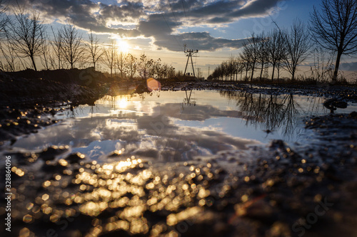 HDR photo of the setting sun reflecting in a puddle.