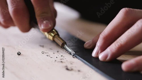 A leather craftsman is cutting the edges of a belt. The master is using an edge beveler tool. photo