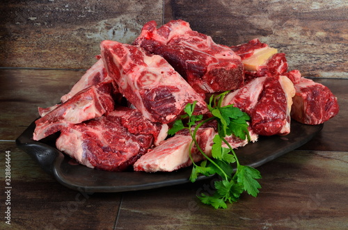 Raw meat with bone on clay plate and brown stone background.Raw meat with beef bone. Beef bone selection for soup