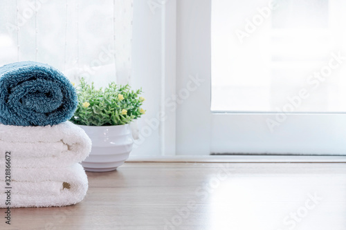 Clean towels and houseplant on wooden table in modern room. Copy space.