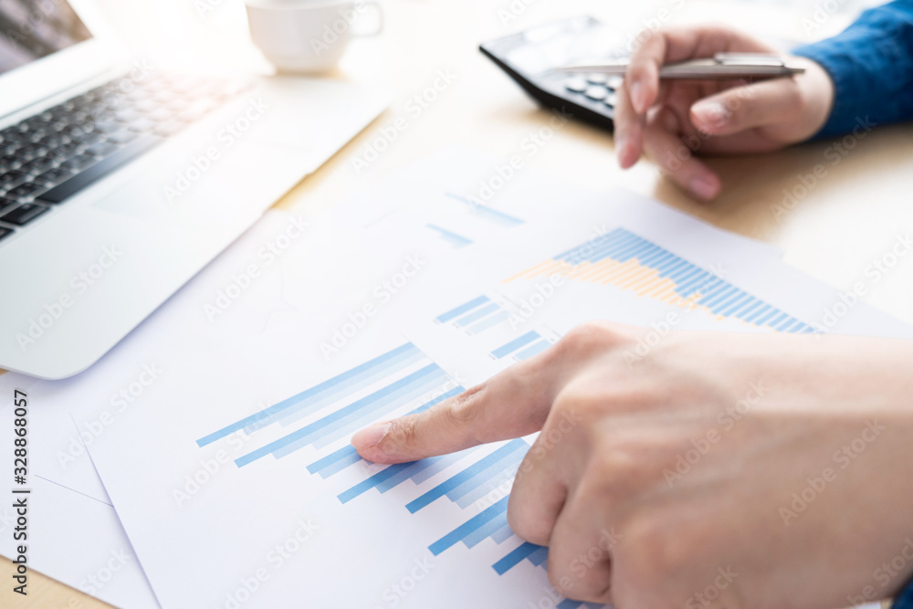 Businessman is inspecting and pointing at the business reports graphs to audit the financial reports. Analyzing the revenue and auditing the budget concept. Businessman is inspecting and pointing at the business reports graphs to audit the financial reports. Analyzing the revenue and auditing the budget concept.