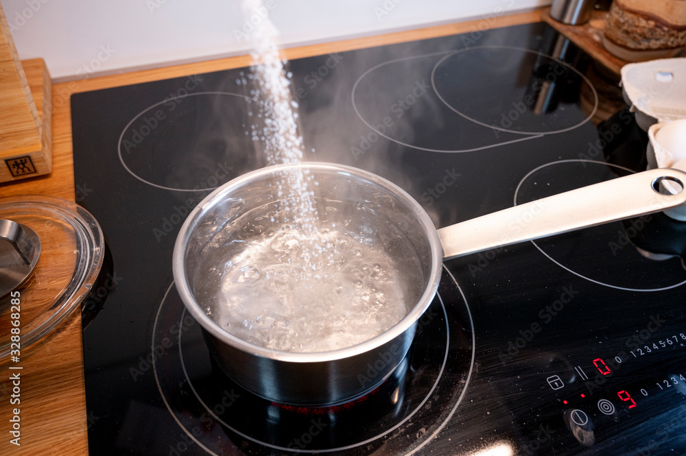 Kochendes wasser in einem kochtopf auf dem herd wird salz hinein gestreut  Stock Photo | Adobe Stock