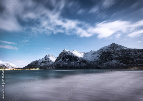 Mountains and reflections on water at night. Winter landscape. The sky with stars and clouds in motion. Nature as a background. Norway - travel