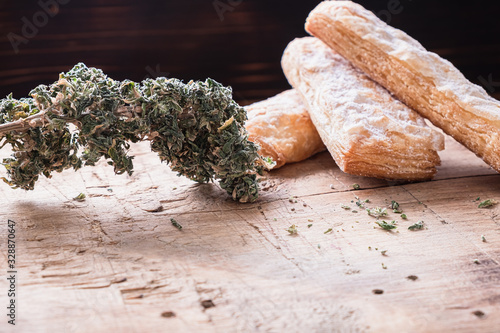 three cookies with marijuana lie on a wooden board. Near big bud cannabis. Horizont photo