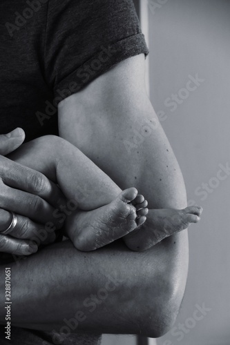 Father holding his newborn baby. Newborn baby feet, black and white photography