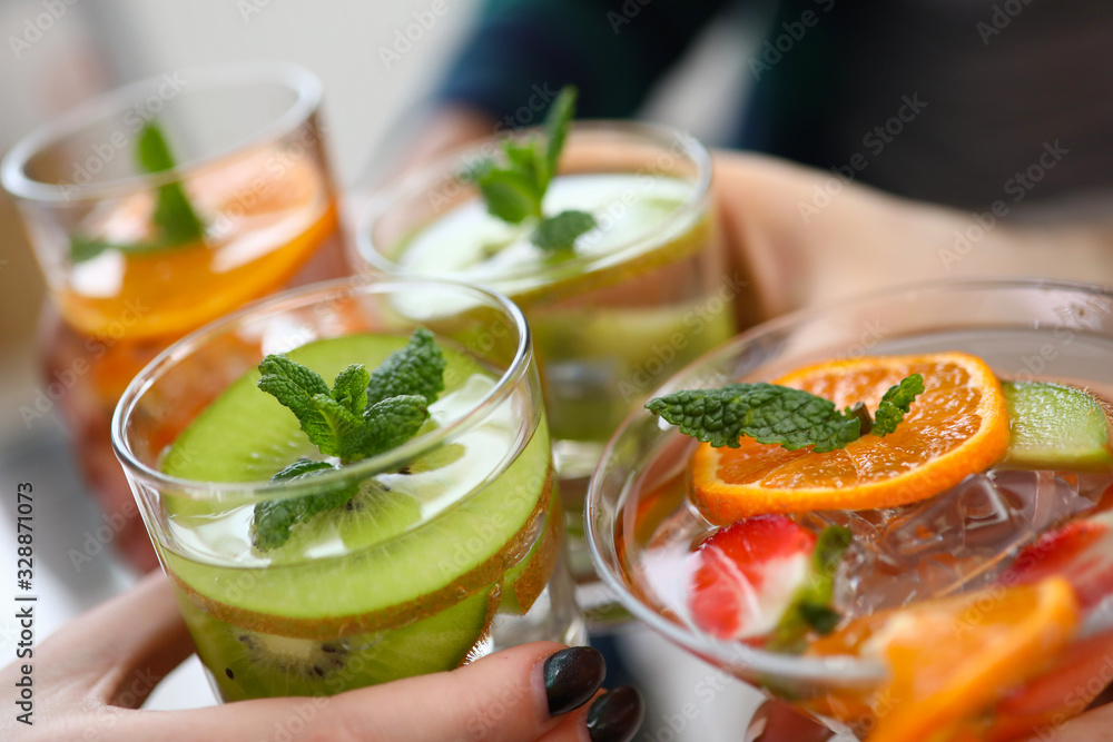 Close-up view of glasses with colourful cocktails and slices of fruits. Yummy drinks on fun party. Orange kiwi strawberry in cooling beverages. Celebration concept Close-up view of glasses with colourful cocktails and slices of fruits. Yummy drinks on fun party. Orange kiwi strawberry in cooling beverages. Celebration concept