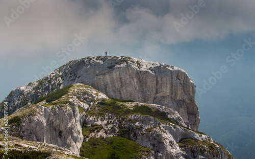 Hiker man standing on a cliff in Retezat National park in Carpathian mountain range, Romania