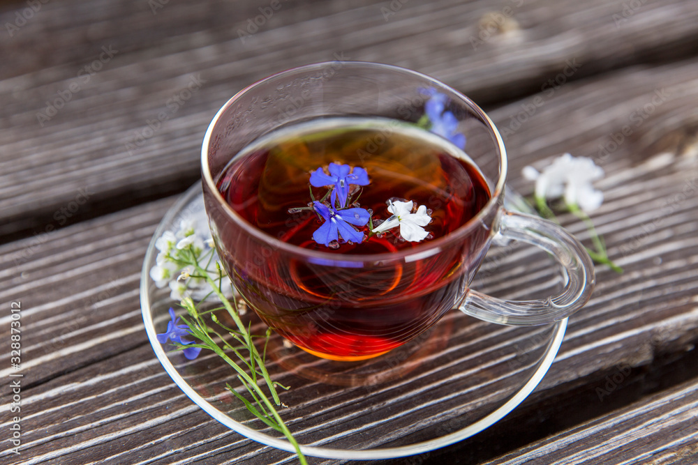 A transparent cup with tea with herbs and small flowers. Health and detox cleansing. A transparent cup with tea with herbs and small flowers. Health and detox cleansing.