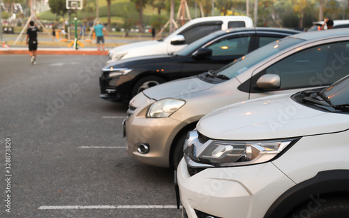 Closeup of front side of white car and other cars parking in outdoor parking lot in twilight evening.  © Amphon