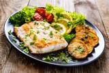 Fish dish - fried cod fillet with potatoes and vegetables on wooden table