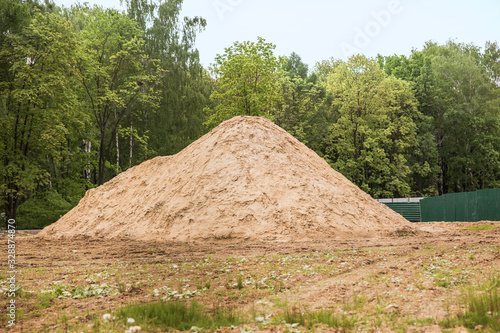 A large mound of sand for construction on the background of trees