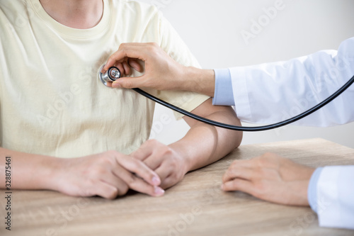 Doctor or nurse advice  to man patient in hospital  while examining the patients pulse  heart rate by stethoscope and hands. Healthcare and medical service.  select focus 