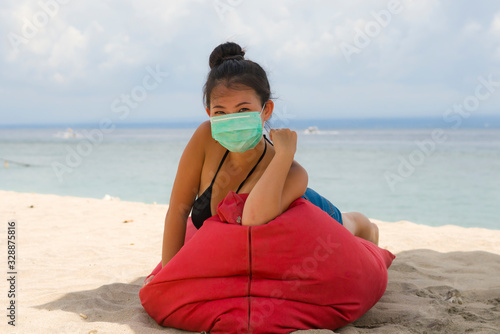young attractive Asian Korean woman enjoying beach holidays wearing bikini and protective facial mask in prevention vs virus infection in use of medical face mask in public places