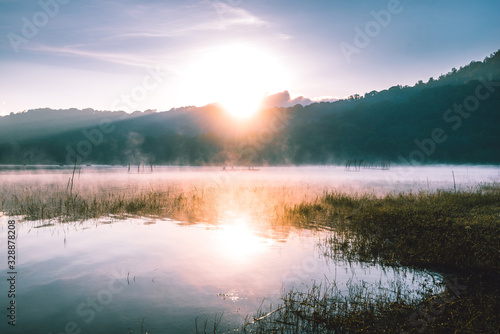 Misty morning sunrise by the lake and mountains