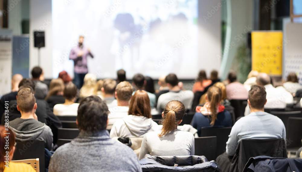 Fototapeta premium Speaker giving a talk in conference hall at business event. Audience at the conference hall. Business and Entrepreneurship concept. Focus on unrecognizable people in audience.