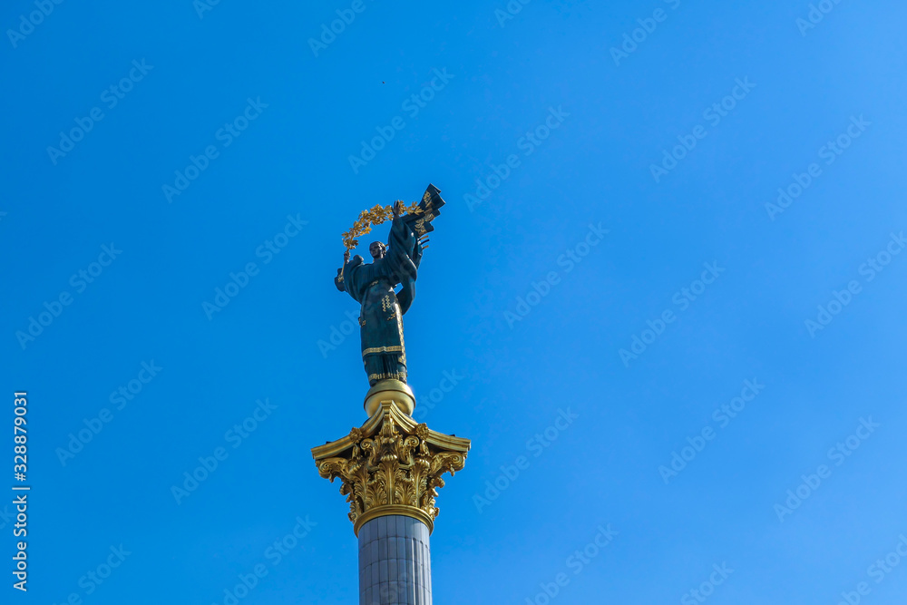 A close-up on Statue of Berehynia, located at the top of victory column on Maidan Nezalezhnosti (Independence Square) in Kiev. A woman is holding  golden branch. Clear and blue sky.