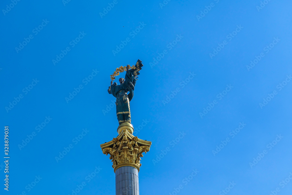 Fototapeta premium A close-up on Statue of Berehynia, located at the top of victory column on Maidan Nezalezhnosti (Independence Square) in Kiev. A woman is holding golden branch. Clear and blue sky.