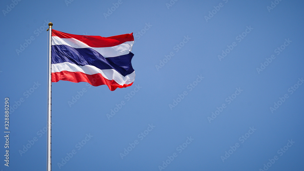 State national flag of Thailand waving on blue sky background.Free space on the side