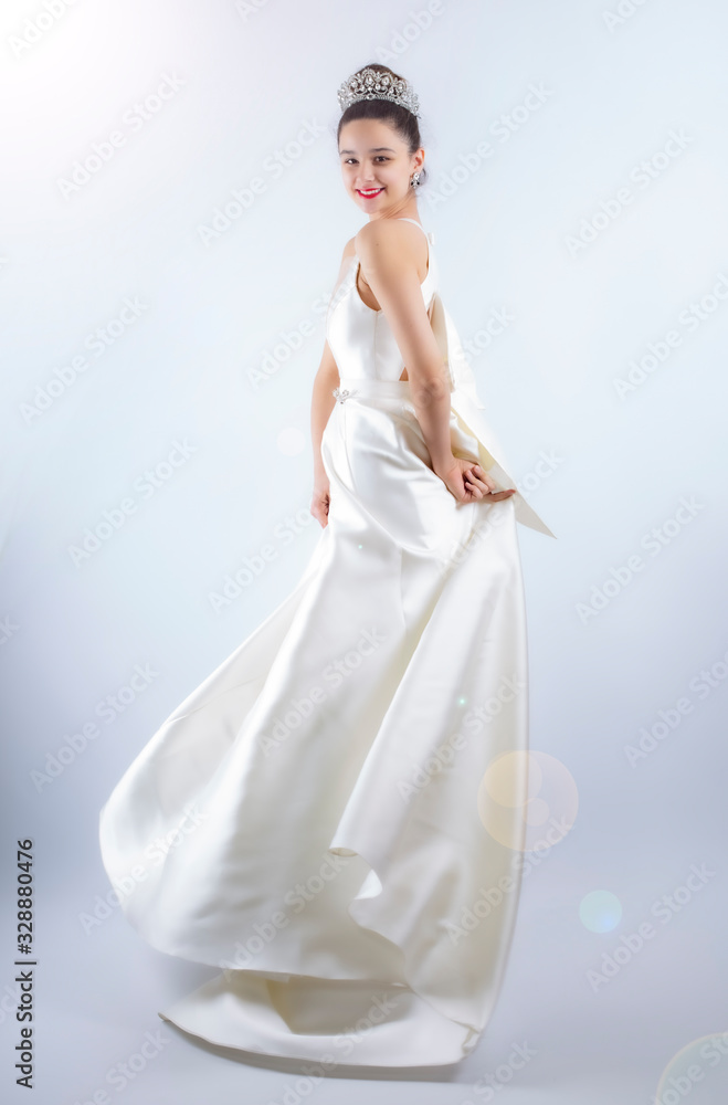 Fototapeta premium Portrait of a beautiful girl in a wedding dress. Dancing Bride, gray background. Isolated