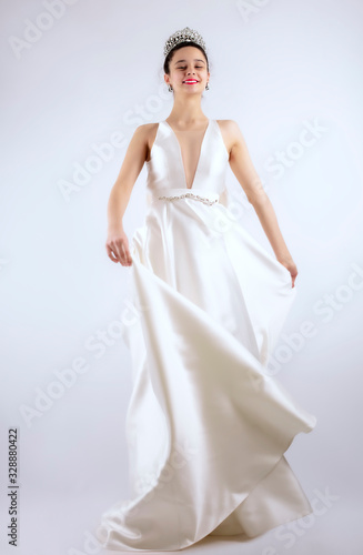 Portrait of a beautiful girl in a wedding dress. Dancing Bride, gray background. Isolated