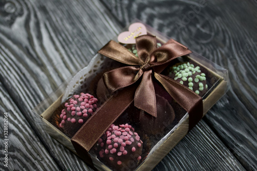 Potato cake coated with chocolate in craft packaging. Garnished with walnut, trickles of chocolate or sprinkled. Against the background of brushed boards.