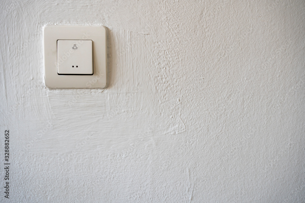 Old plastic switch with a bulb symbol on a white wall with copy space Old plastic switch with a bulb symbol on a white wall with copy space