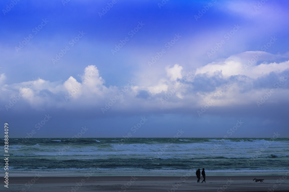 A couple walks along Zurriola beach with a lot of wind and bad weather, Donostia City, Euskadi