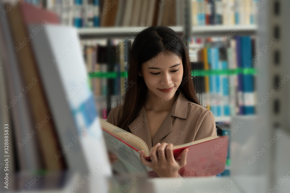 In the library,Asian student search book at shelves.
