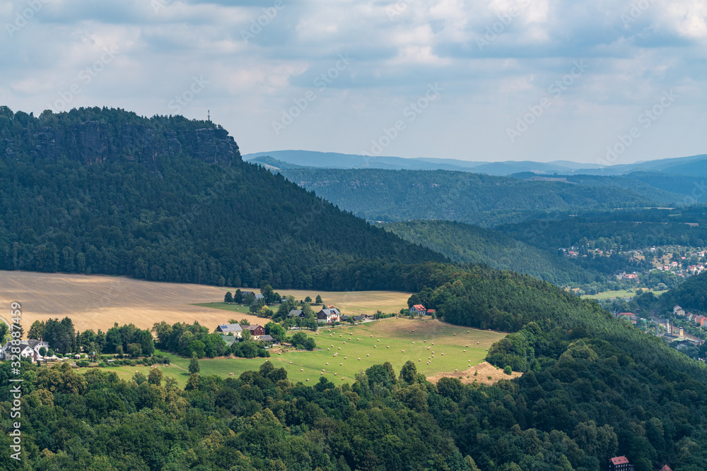 Königstein fortress on the banks of the Elbe river, green landscape with mountains in the background. Dresden, Saxon Switzerland, Germany.