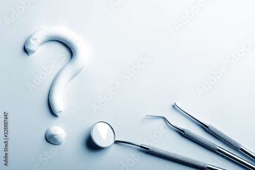 Dental instruments and a tooth paste question mark in blue monochrome. Dental treatment concept.