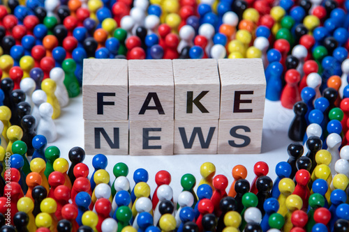 Fotografie fakenews text on wooden cubes, surrounded by wooden figurines in several colours