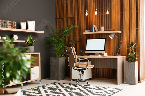 Foto Comfortable workplace with computer near wooden wall in stylish room interior