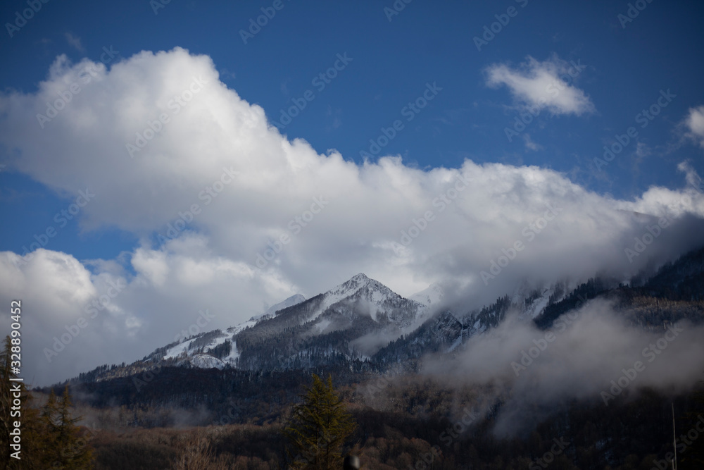 Mountain landscape in early spring. The fog slides from the mountains. Snow peaks. Ski resort. Beautiful highland background. Wide view of the mountain range. The calm of northern nature. Mountain landscape in early spring. The fog slides from the mountains. Snow peaks. Ski resort. Beautiful highland background. Wide view of the mountain range. The calm of northern nature.