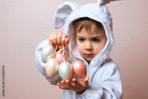 Cute little child boy wearing bunny costume on Easter day. Boy with Easter eggs in the basket.
