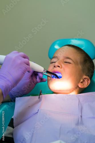 Dentists with a patient during a dental intervention to boy. Dentist Concept. At dentist's office. vertical photo