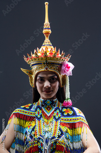 The beautiful woman wearing Thai southern folk dancing costume,made from colorful bead,put headdress on her head,model posing on solid backdrop