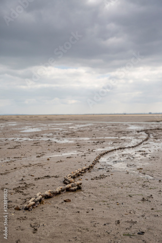 Fishing boat anchor chain stuck on the beach in low tide period.