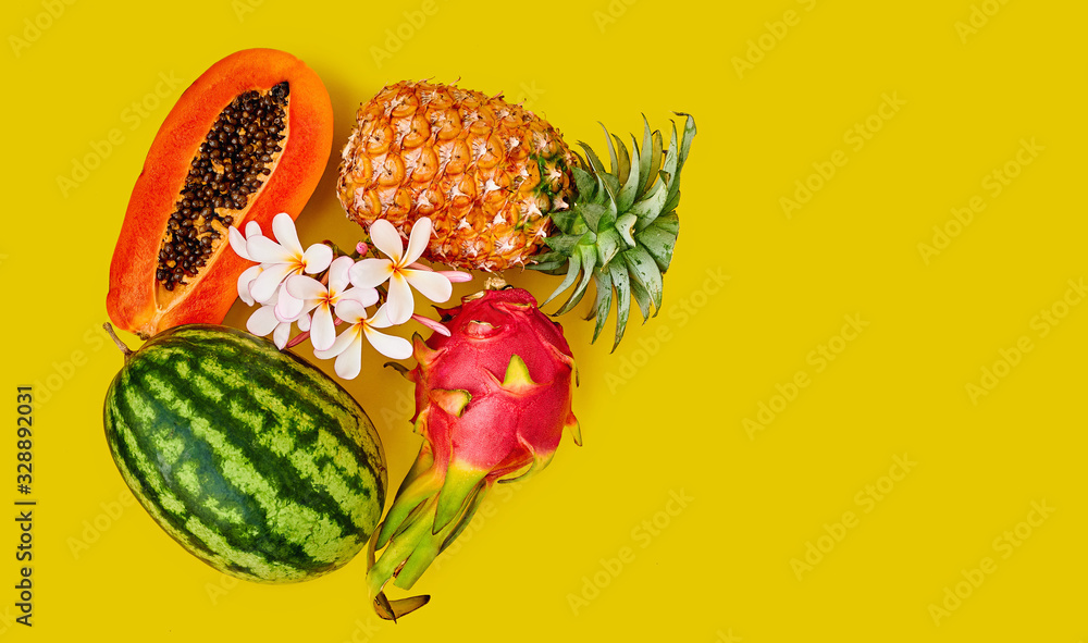 Tropical fruits - pineapple, dragon, watermelon and half papaya on a yellow background. Tropical flower. Space for text Tropical fruits - pineapple, dragon, watermelon and half papaya on a yellow background. Tropical flower. Space for text