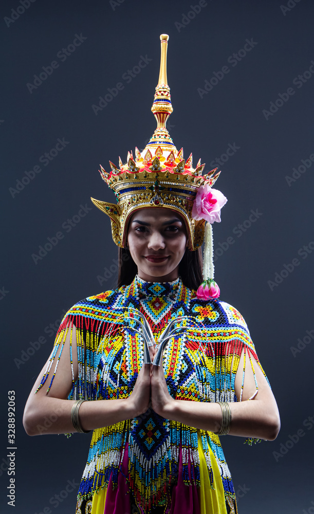Obraz premium The beautiful woman wearing Thai southern folk dancing costume,made from colorful bead,put headdress on her head,prepare for racticing and showing preformances,on solid backdrop
