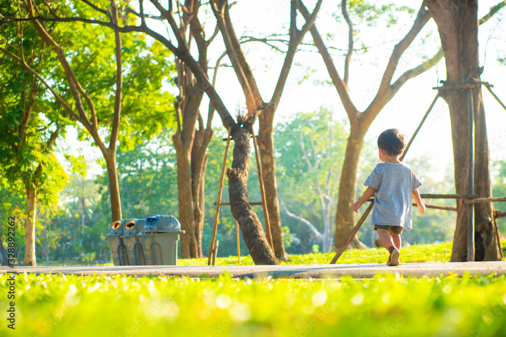 Adorable little asian boy walking on green grass sunset light in summer park