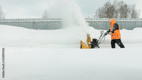 Man cleans snow with a snow thrower goes right to left